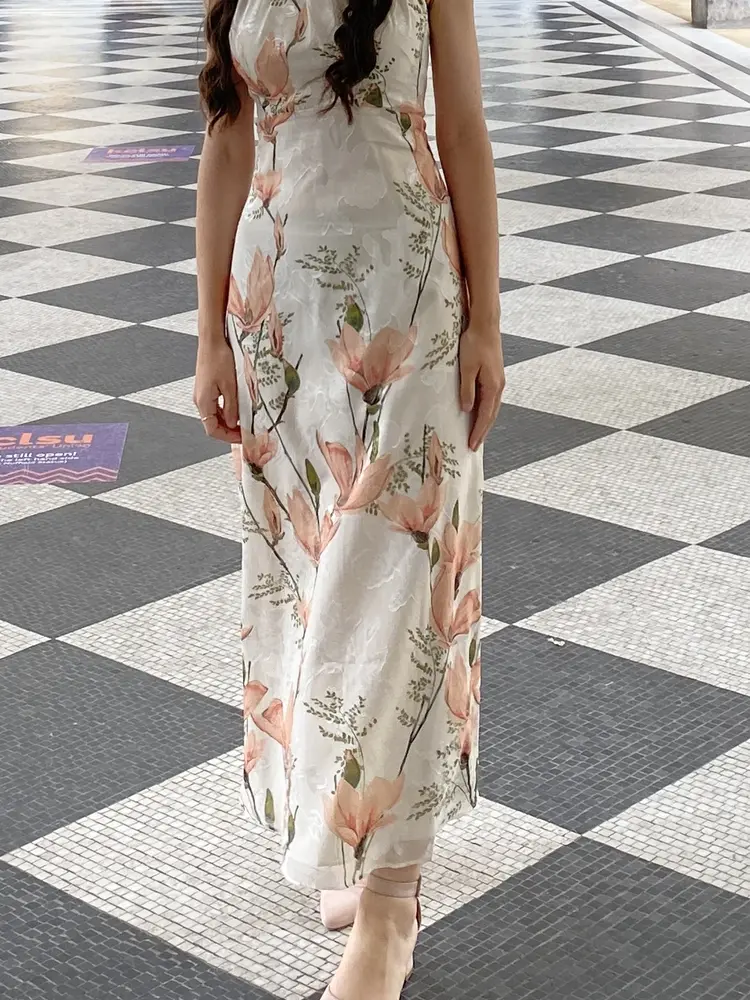 Woman wearing a cream floral maxi dress altered to length
